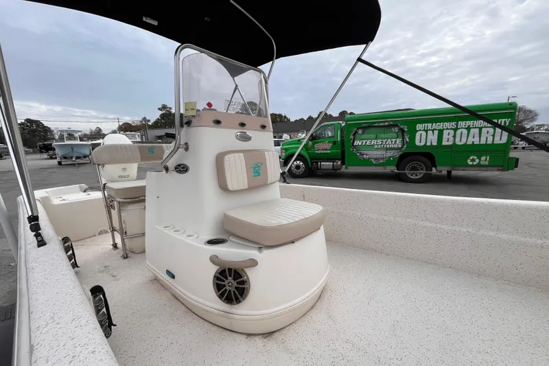 Slide: The Image of 2019 Carolina Skiff 20 JVX CC boat interior with seating and console, parked near green truck. - 9