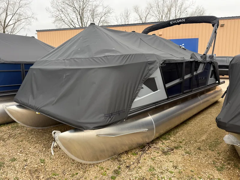 The Image of 2026 Sylvan R-20 PARTY FISH pontoon boat with cover on gravel surface. - 0