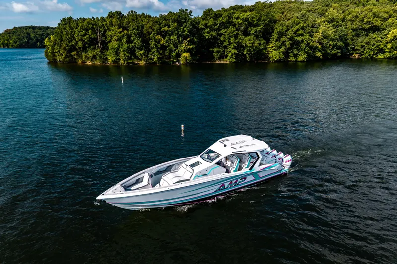 Slide: The Image of 2025 AMP 443 boat cruising on a scenic lake with lush green forest backdrop. - 28