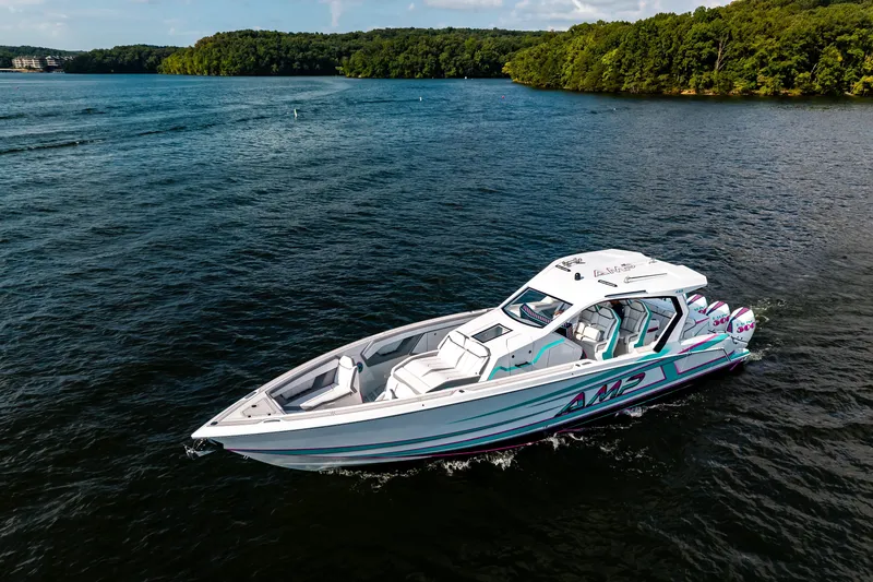 Slide: The Image of 2025 AMP 443 boat cruising on a scenic lake with lush green shoreline. - 32