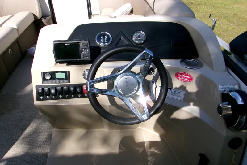 Slide: The Image of 2023 Crest Classic DLX 220 L boat dashboard with steering wheel and controls. - 4