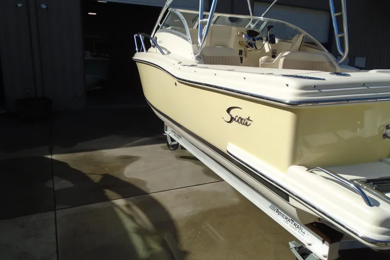 Slide: The Image of 2004 Scout 242 Abaco boat on trailer, beige exterior, parked outside a garage. - 15