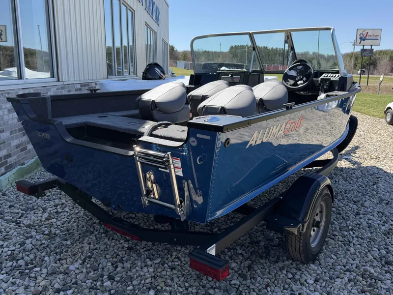 Slide: The Image of 2026 Alumacraft CLASSIC 165/SP boat on trailer, blue, parked outdoors. - 7