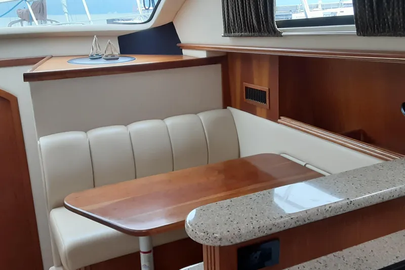 Slide: The Image of Interior of 2003 Cruisers Yachts 4050 Express with cozy dining area and wooden accents. - 19