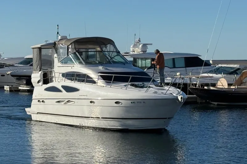 The Image of 2003 Cruisers Yachts 4050 Express in marina, person on deck, clear sky. - 0