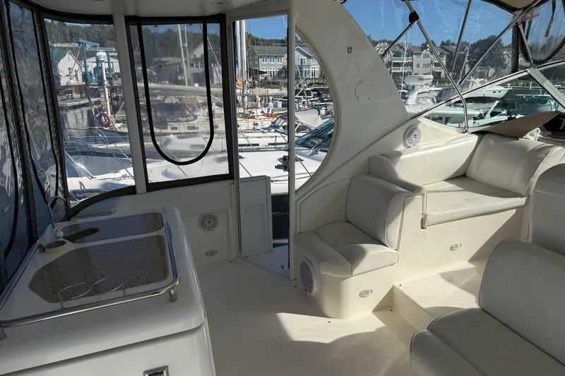 Slide: The Image of 2003 Cruisers Yachts 4050 Express interior with white seating and marina view. - 9