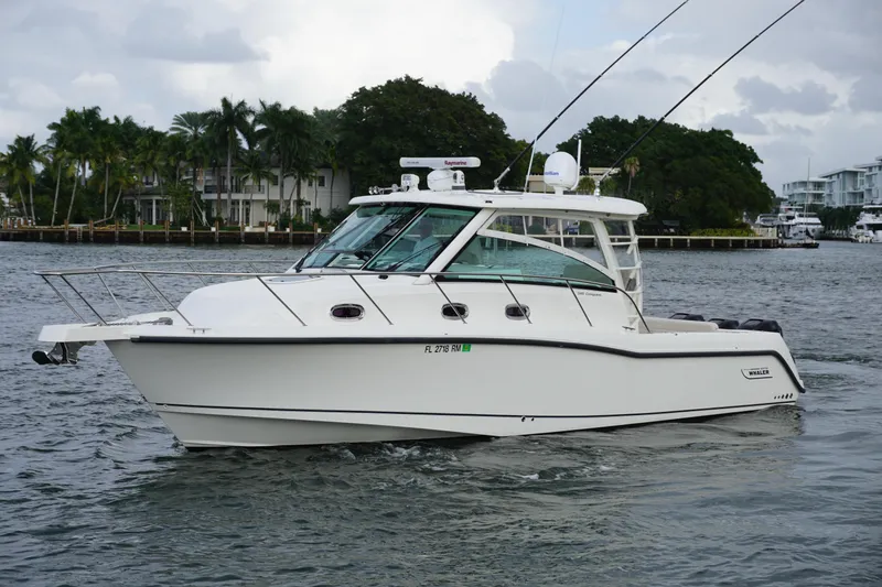 The Image of 2015 Boston Whaler 345 Conquest boat cruising in a marina with palm trees and yachts. - 0