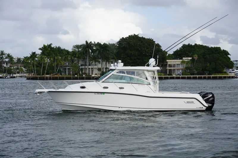 Slide: The Image of 2015 Boston Whaler 345 Conquest boat cruising on a sunny day near waterfront homes. - 2