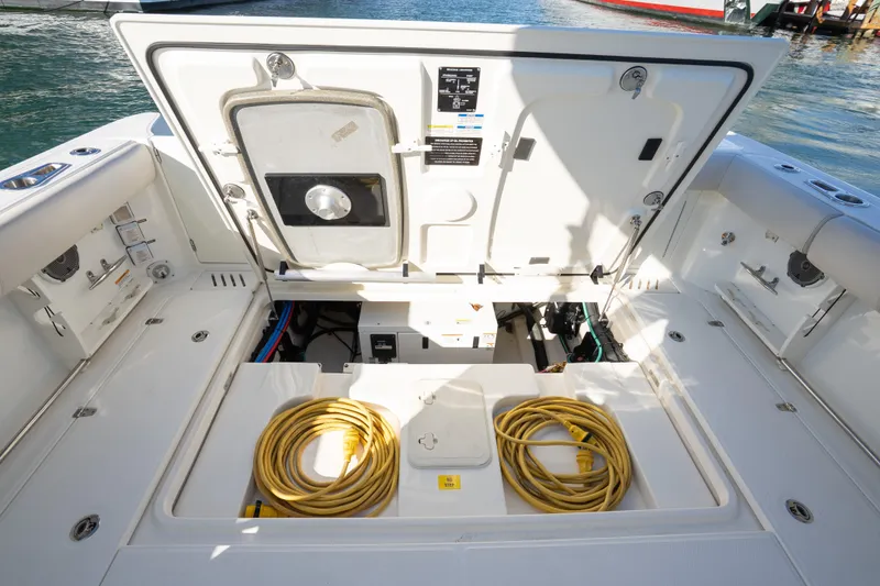 Slide: The Image of 2015 Boston Whaler 345 Conquest boat deck with open storage compartment and yellow cables. - 29