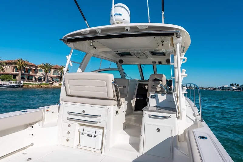 Slide: The Image of 2015 Boston Whaler 345 Conquest boat interior with seating, ocean view, and luxury homes in background. - 36