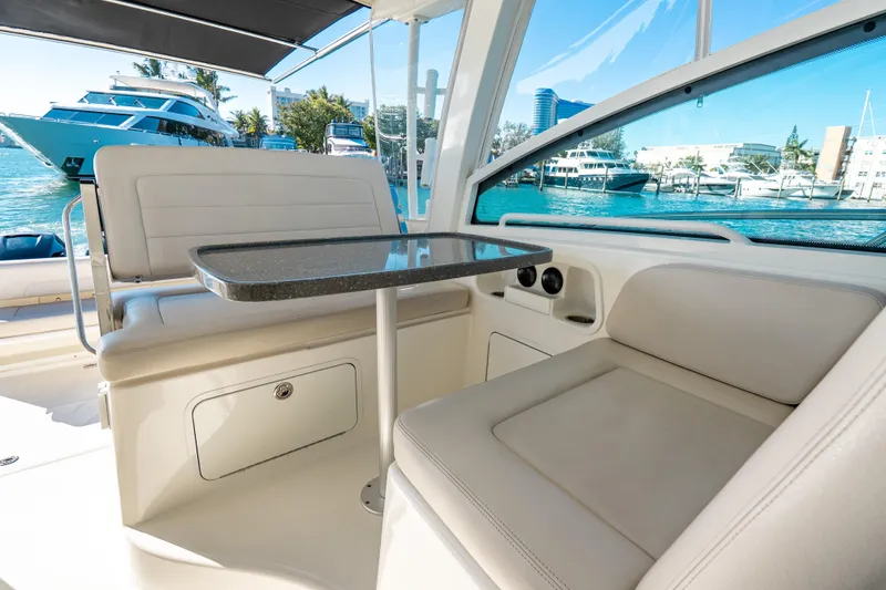 Slide: The Image of 2015 Boston Whaler 345 Conquest interior with seating and table, docked near yachts. - 43