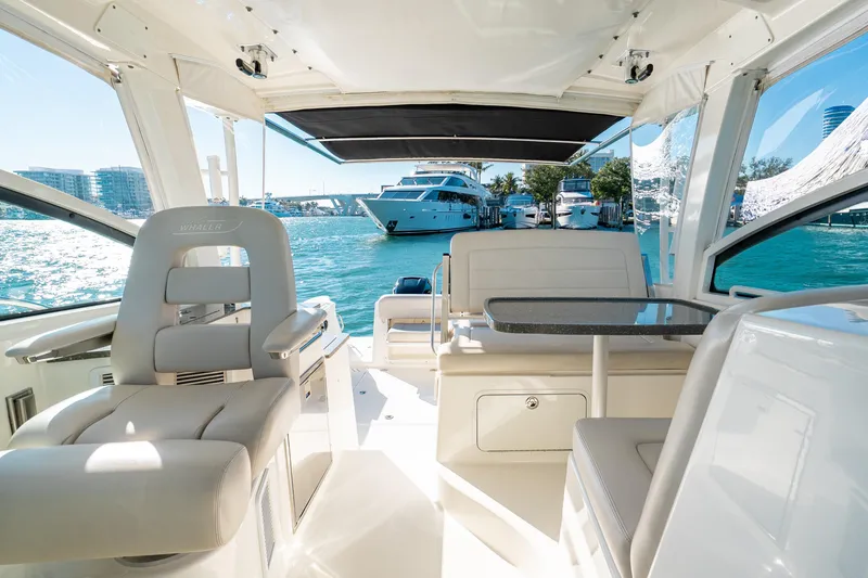 Slide: The Image of 2015 Boston Whaler 345 Conquest interior with seating and table, docked near yachts. - 50
