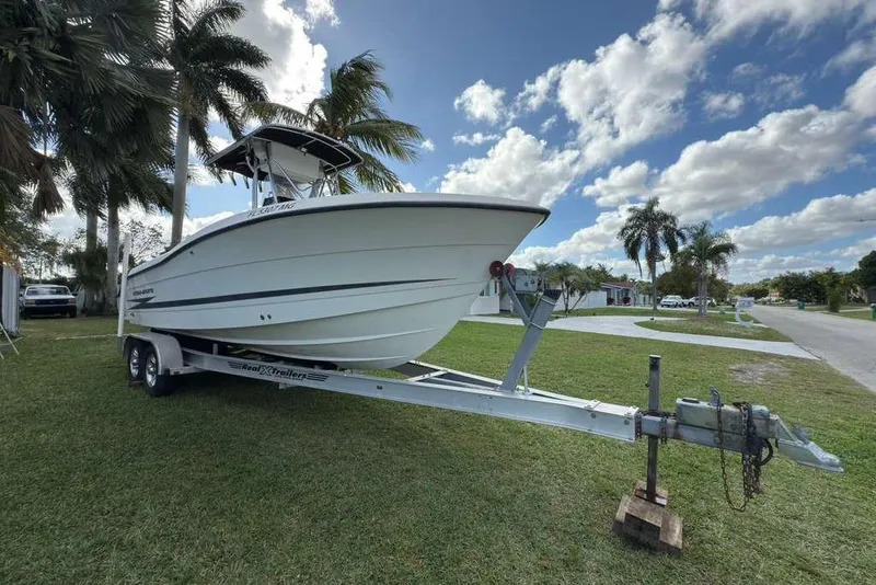 Slide: The Image of 2003 Hydra-Sports Vector 2400 CC boat on trailer, parked on grass under palm trees. - 2