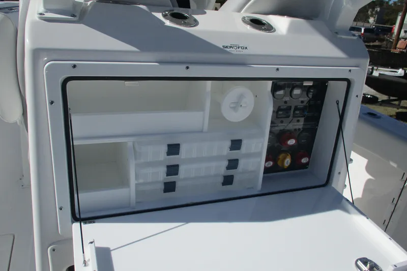 Slide: The Image of 2026 Sea Fox 288 Commander storage compartment with organized tackle boxes and control panel. - 8