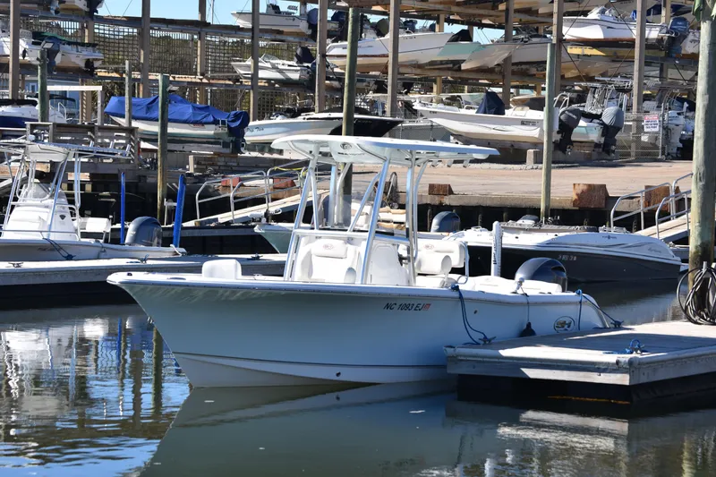 Slide: The Image of 2018 Sea Hunt Ultra 225 boat docked at marina with multiple boats in background. - 10