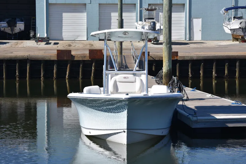 Slide: The Image of 2018 Sea Hunt Ultra 225 boat docked at marina with blue building background. - 11
