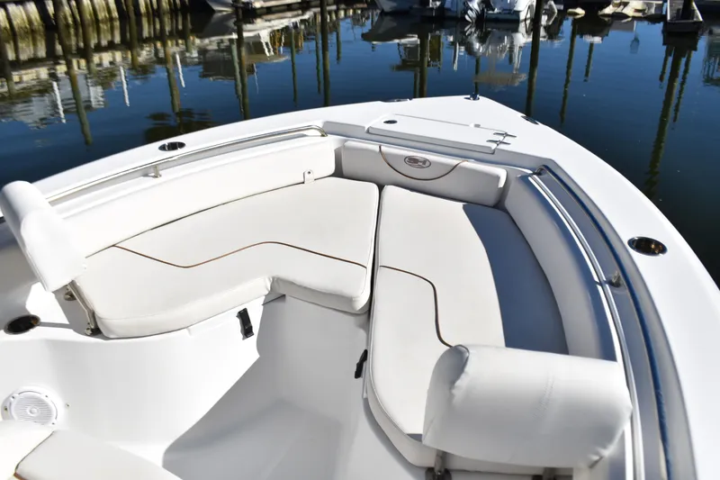Slide: The Image of 2018 Sea Hunt Ultra 225 boat with white cushioned seating in a marina. - 12