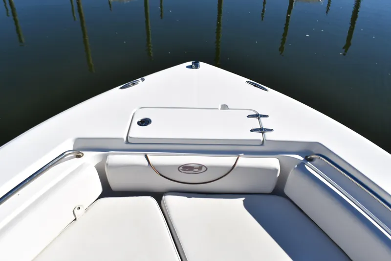 Slide: The Image of 2018 Sea Hunt Ultra 225 boat bow with seating and storage, docked on calm water. - 15