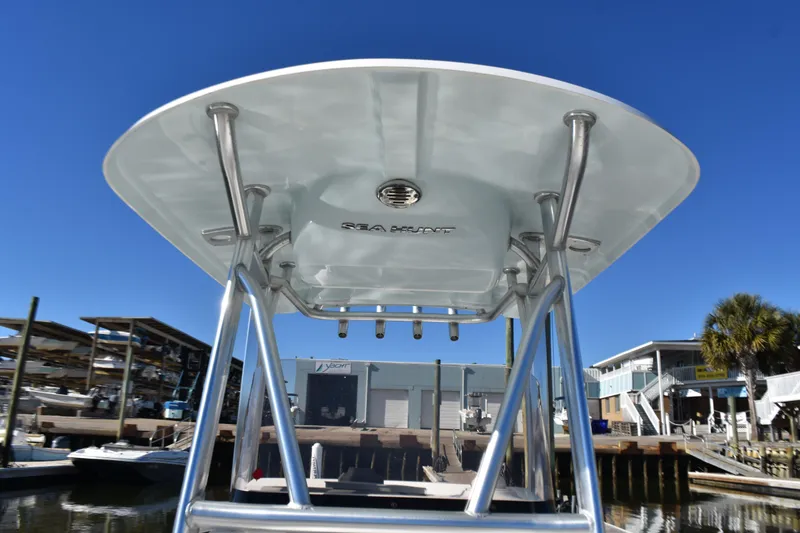 Slide: The Image of 2018 Sea Hunt Ultra 225 boat with T-top, docked under clear blue sky. - 19