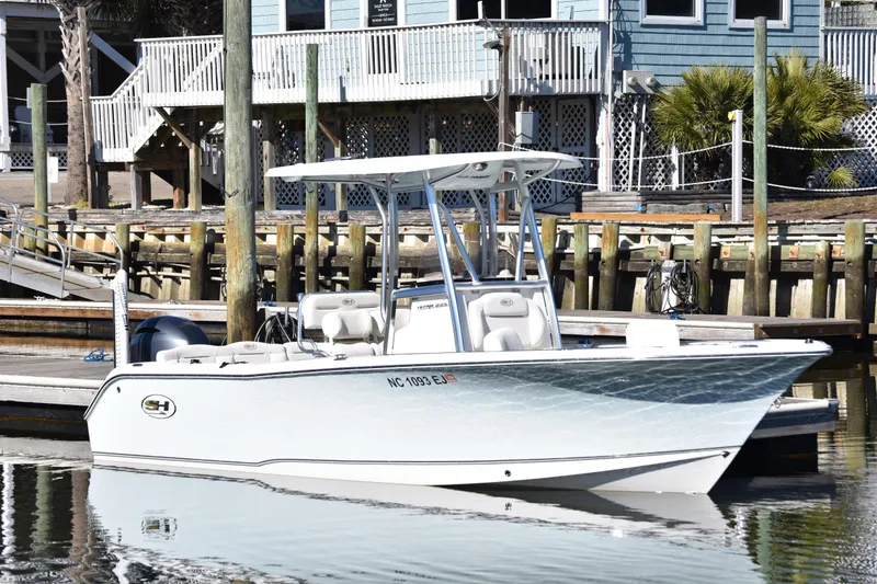 The Image of 2018 Sea Hunt Ultra 225 boat docked at a marina with waterfront buildings. - 4