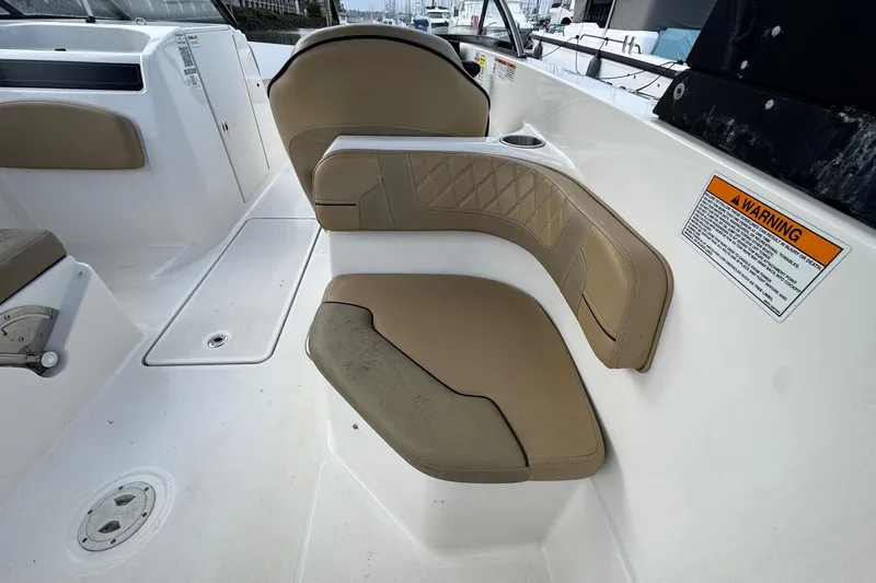 Slide: The Image of 2022 Bayliner VR6 Bowrider OB interior seating with tan upholstery and warning label. - 14