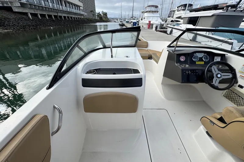 Slide: The Image of 2022 Bayliner VR6 Bowrider OB interior with steering wheel and seating, docked at marina. - 27