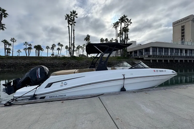 Slide: The Image of 2022 Bayliner VR6 Bowrider OB docked by palm trees and a hotel. - 4