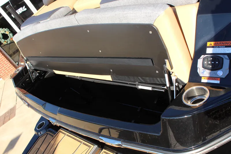 Slide: The Image of 2026 Tigé 24RZX boat storage compartment with open lid, showcasing spacious interior and cup holder. - 12