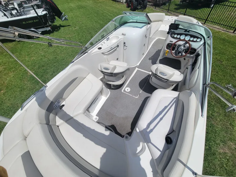 Slide: The Image of 2007 Chaparral Sunesta 214 boat interior with seating and steering wheel, parked on grass. - 13