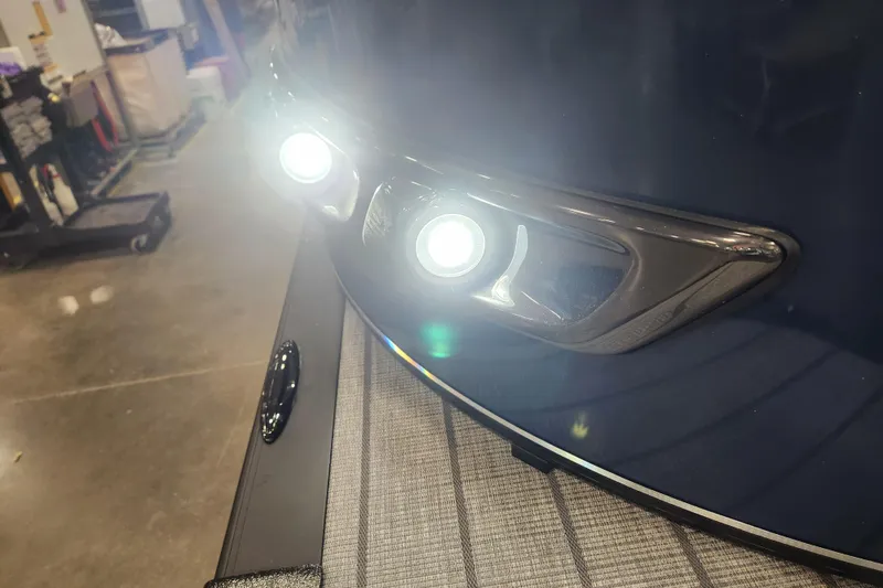 Slide: The Image of 2026 Tahoe Pontoon 25 Cascade Quad Lounge with illuminated front lights in a workshop setting. - 48