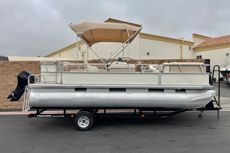 The Image of 2004 Sun Tracker Party Barge 21 pontoon boat on trailer, beige canopy, outdoor setting. - 0