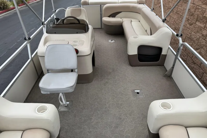 Slide: The Image of 2004 Sun Tracker Party Barge 21 interior with beige seating and steering console. - 12