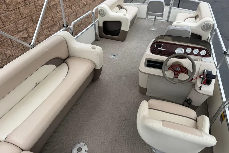Slide: The Image of 2004 Sun Tracker Party Barge 21 interior with beige seating and steering console. - 18