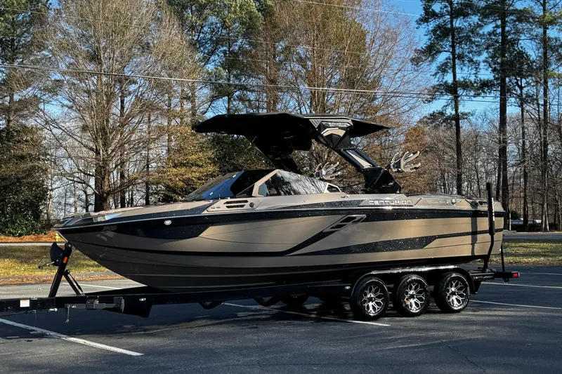 Slide: The Image of 2025 Centurion Ri245 boat on trailer, parked outdoors with trees in background. - 20