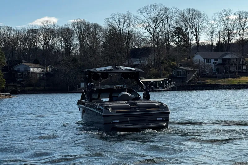 Slide: The Image of 2025 Centurion Ri245 boat cruising on a scenic lake with houses in the background. - 5