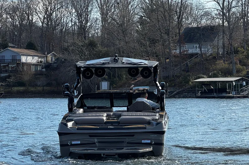 Slide: The Image of 2025 Centurion Ri245 boat cruising on a lake near waterfront homes. - 6