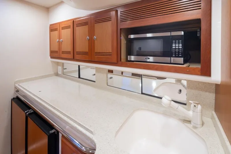 Slide: The Image of 2006 Cabo 40 Express yacht kitchen with microwave, wooden cabinets, and sink. - 18
