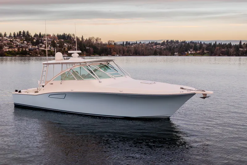 Slide: The Image of 2006 Cabo 40 Express boat on calm water with scenic shoreline background. - 5