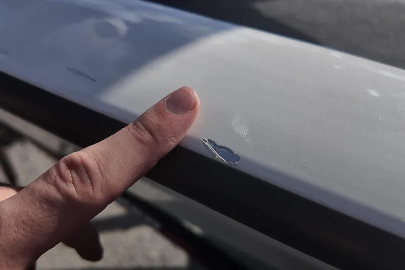 Slide: The Image of Close-up of a finger pointing at a scratch on a 2021 Tracker Pro Team 190 TX. - 17
