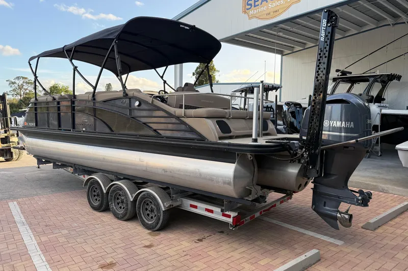 Slide: The Image of 2018 Bennington 25 QSB pontoon boat on trailer, parked near palm trees. - 5