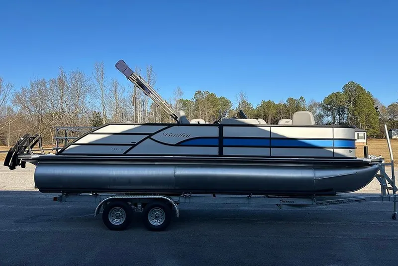 Slide: The Image of 2026 Bentley Pontoons Fish 243 Swingback on trailer, parked outdoors under clear blue sky. - 8