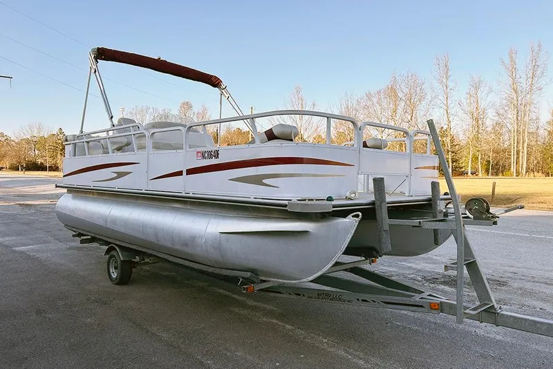 Slide: The Image of 2006 Bentley Pontoons 200 Fish on trailer, parked outdoors, clear sky background. - 2