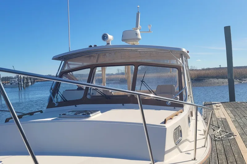 Slide: The Image of 2015 Fortier 30 boat docked by a serene waterfront under clear blue skies. - 4