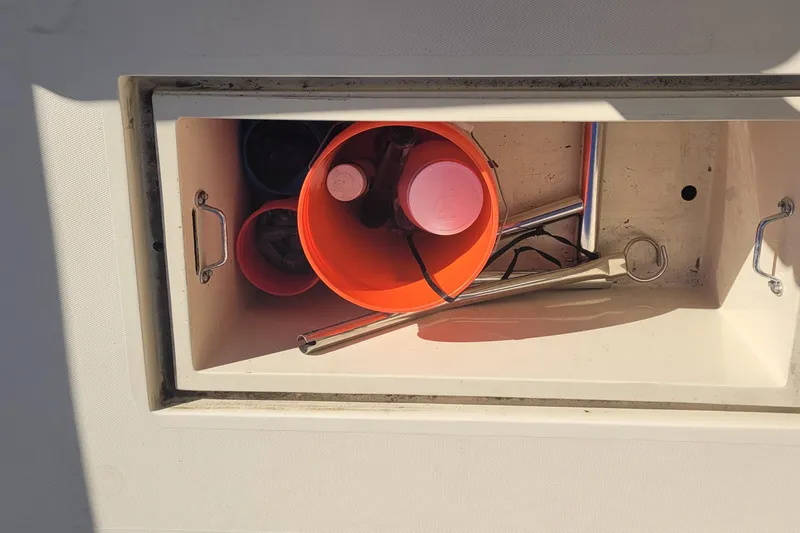 Slide: The Image of Storage compartment on 2015 Fortier 30 boat with orange bucket and metal tools. - 58
