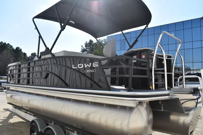 Slide: The Image of 2026 Lowe SF 232 Sport Fish pontoon boat with canopy, parked on a trailer. - 7