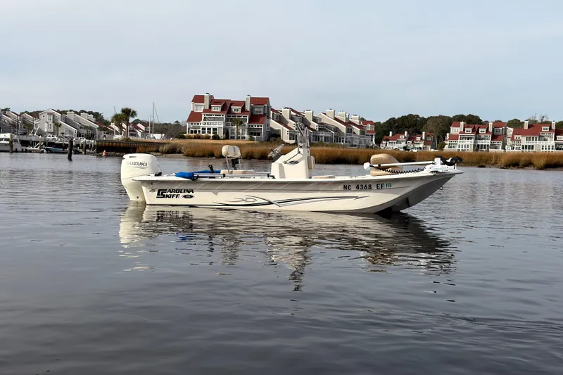 Slide: The Image of 2017 Carolina Skiff 18 JVX CC boat on calm water near waterfront homes. - 1
