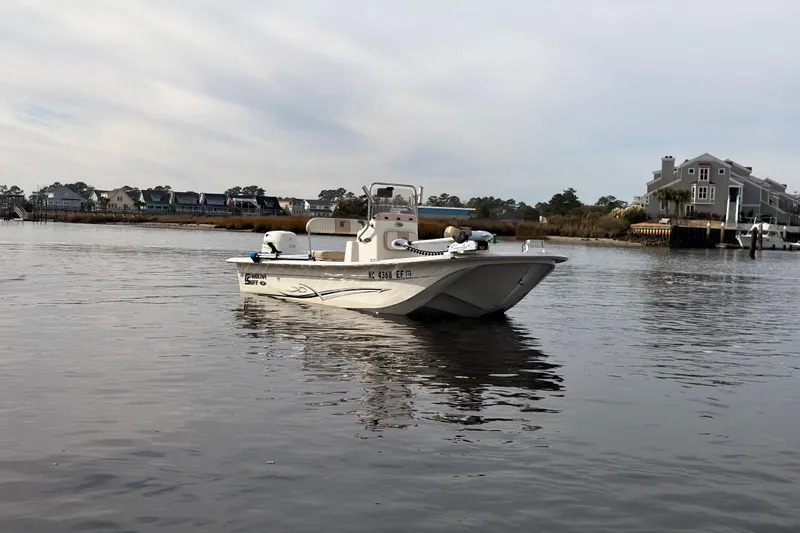Slide: The Image of 2017 Carolina Skiff 18 JVX CC boat on calm water near waterfront homes. - 10