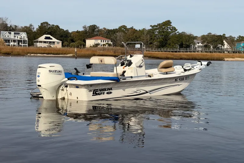 Slide: The Image of 2017 Carolina Skiff 18 JVX CC boat on calm water with Suzuki engine. - 2