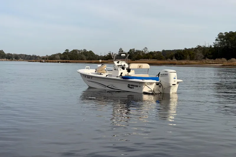 Slide: The Image of 2017 Carolina Skiff 18 JVX CC boat on calm water, featuring Suzuki outboard motor. - 3