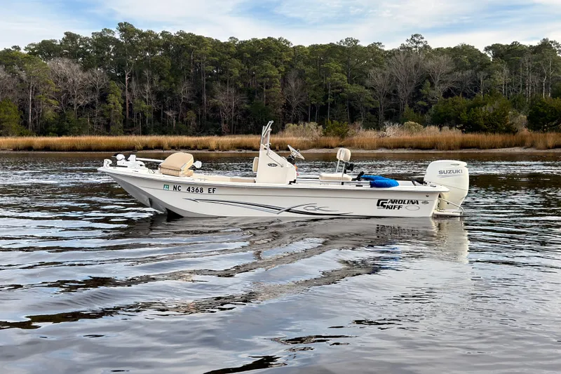 Slide: The Image of 2017 Carolina Skiff 18 JVX CC boat on calm water with forested background. - 4